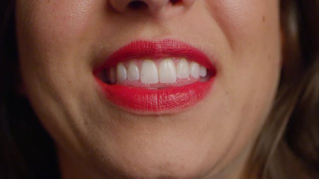 Caucasian woman in red lipstick gives camera a toothy smile.