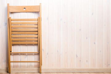 one wooden folding chair and a place right on the wall