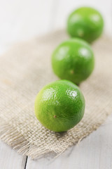 Three limes on a wooden table.
