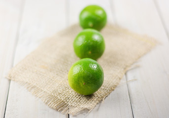 Three limes on a wooden table.