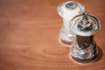 Glass salt and pepper shakers on wooden background