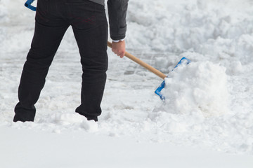 Business man with shovel cleaning snow filled street in front of the office at work