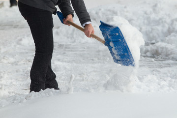 Business man with shovel cleaning snow filled street in front of the office at work