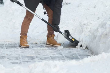 Business woman with shovel cleaning snow filled street in front of the office at work © sefoma