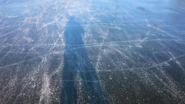 Shadow of a man Ice skating on a frozen lake near the river IJssel in The Netherlands during a beautiful winter day