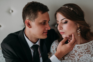 cute wedding couple in the interior of a classic white studio decorated. hey kiss and hug each other, holding hands looking at each other