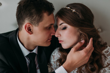 cute wedding couple in the interior of a classic white studio decorated. hey kiss and hug each other, holding hands looking at each other