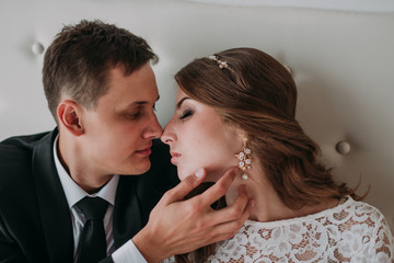 cute wedding couple in the interior of a classic white studio decorated. hey kiss and hug each other, holding hands looking at each other