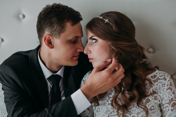 cute wedding couple in the interior of a classic white studio decorated. hey kiss and hug each other, holding hands looking at each other