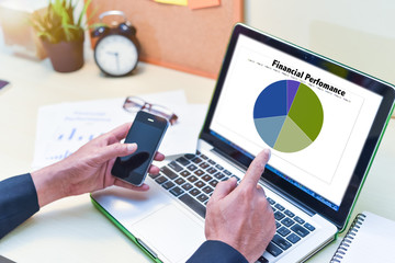 Financial Planning Concept,man is working by using a laptop with finger pointing at computer screen with hand holding smart phone.