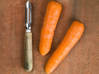 Raw Uncooked Organic Carrots With a Vegetable Peeler Kitchen Utensil
