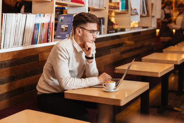 Serious young man chatting by laptop computer.