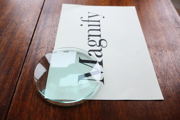 Magnify graphic text with glass lens on white paper