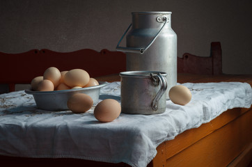 Still life in a rustic style: set of aluminum cookware and eggs on a wooden table. Natural light from the windows. © symbol344