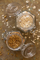 Toasted oat grains and oat flakes in swing top jars, photographed overhead on slate with natural light (Selective Focus, Focus on the top of the oats)