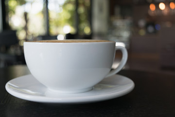 Cup of coffee on wooden table in cafe.