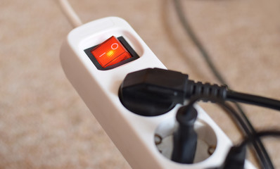 Elektroenergie sparen im Haushalt. Konzeptbild zu der Energiekrise. Weiße Steckdose mit schwarzen...