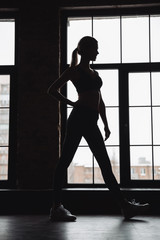 Fototapeta na wymiar Silhouette of woman athlete standing near the window