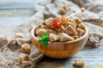 Wooden bowl with cubes of cane sugar and stick with crystal suga
