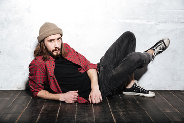 Concentrated bearded hipster man posing over wall background.