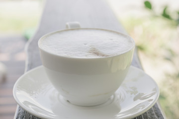 Cup of coffee on wooden table in cafe.