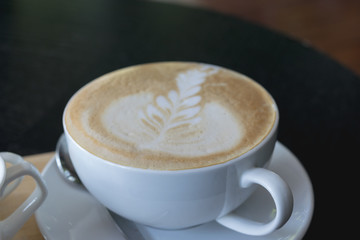 Cup of coffee on wooden table in cafe.