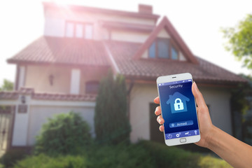 Smartphone with home security app in a hand on the building background - 135081572