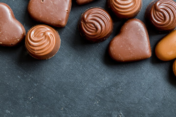 Chocolate hearts candies on black background Top view Copy space Valentines day postcard concept