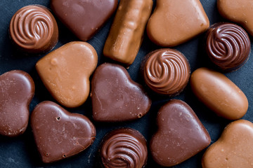 Chocolate hearts candies on black background Top view Copy space Valentines day postcard concept