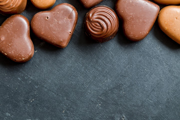 Chocolate hearts candies on black background Top view Copy space Valentines day postcard concept