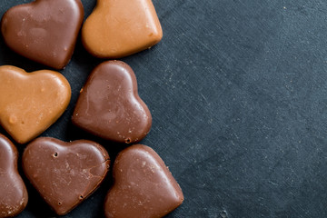 Chocolate hearts candies on black background Top view Copy space Valentines day postcard concept