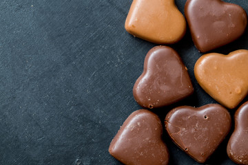 Chocolate hearts candies on black background Top view Copy space Valentines day postcard concept