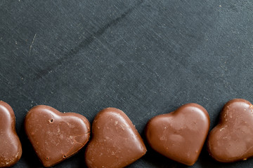 Chocolate hearts candies on black background Top view Copy space Valentines day postcard concept