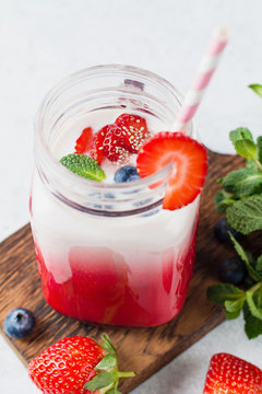 Strawberry smoothie in glass jar with cocktail tube for drinking. Refreshing cold summer drink