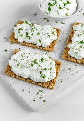 Homemade Crispbread toast with Cottage Cheese and parsley on white wooden board.