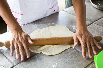 Woman rolling out the pizza dough with a rolling pin