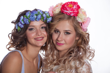 Two young and beautiful girls on a white background with flowers in her hair