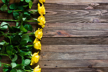 Romantic background with the yellow roses on a wooden table