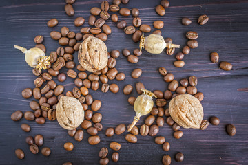 Fototapeta na wymiar Coffee beans with walnuts and poppy seeds on a wooden background