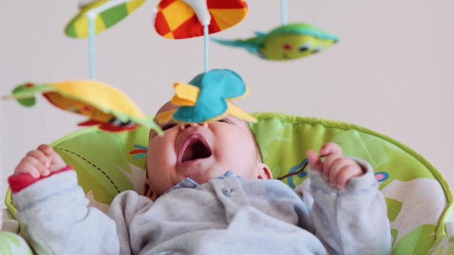 Little cute baby swinging and looking toys