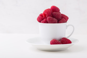 Fresh raspberry berries in a cup on white background