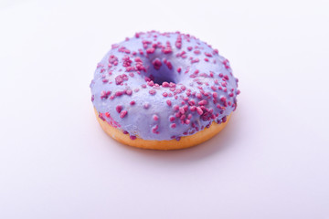 Purple donut with chocolate sprinkles on a light background