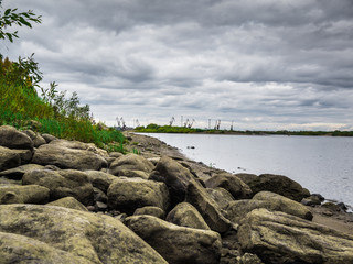 Port in Pechora river in the north of Russia and boulders in the foreground