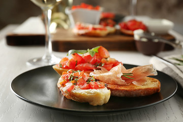 Tasty bruschetta on black plate, close up