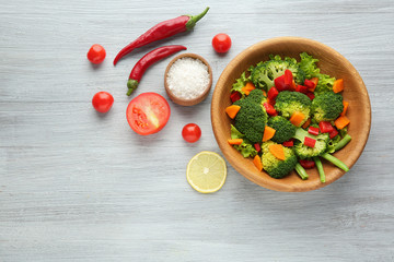 Bowl with fresh vegetables on wooden background