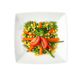 Plate with fresh vegetables on light background