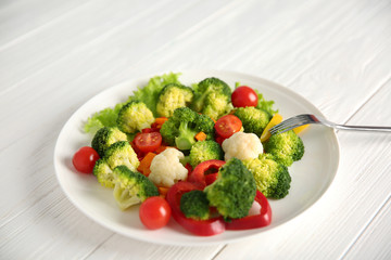 Plate with fresh vegetables on wooden background