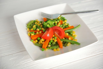 Plate with fresh vegetables on wooden background