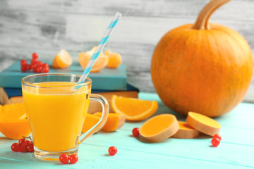 Fresh pumpkin smoothie with oranges and books on table