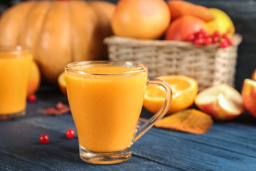 Glass of pumpkin smoothie on wooden background